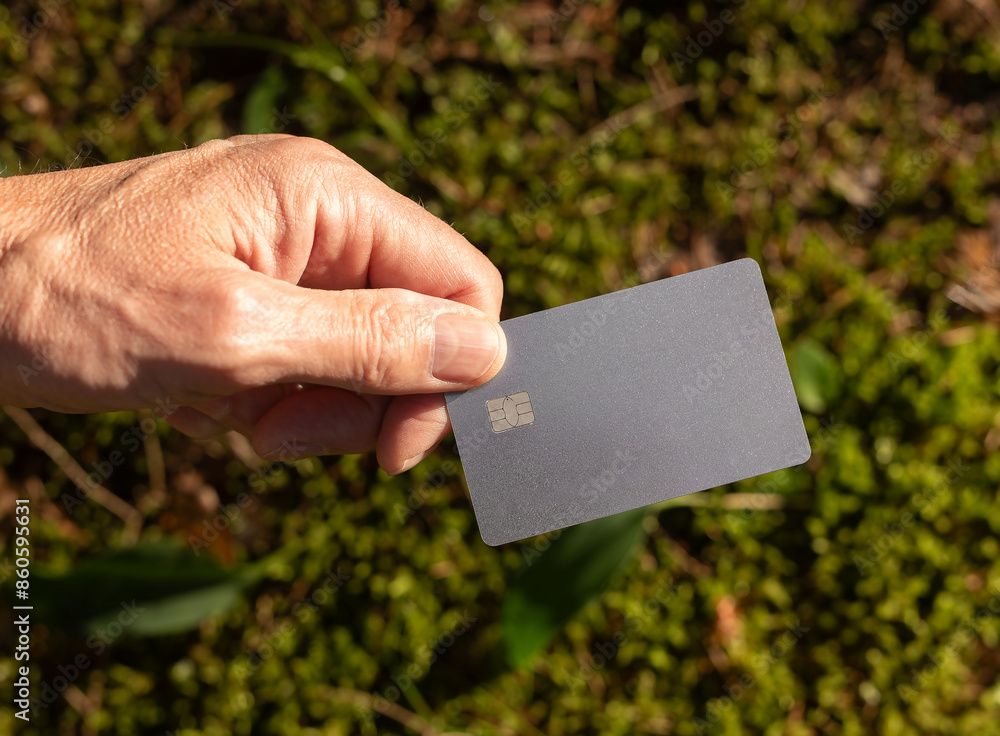 . Blank bank debit card mockup in male hand in nature, sunny summer day, green plants, grass background. . Blank bank debit card mockup in male hand in nature, sunny summer day, green plants, grass background.