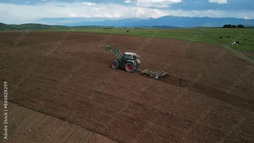 Drone view of tractor plowing field in cultivated land and soil tillage. Concept of work in agronomic farm for making business with organic food. Farmer is preparing field for new crops Drone view of tractor plowing field in cultivated land and soil tillage. Concept of work in agronomic farm for making business with organic food. Farmer is preparing field for new crops