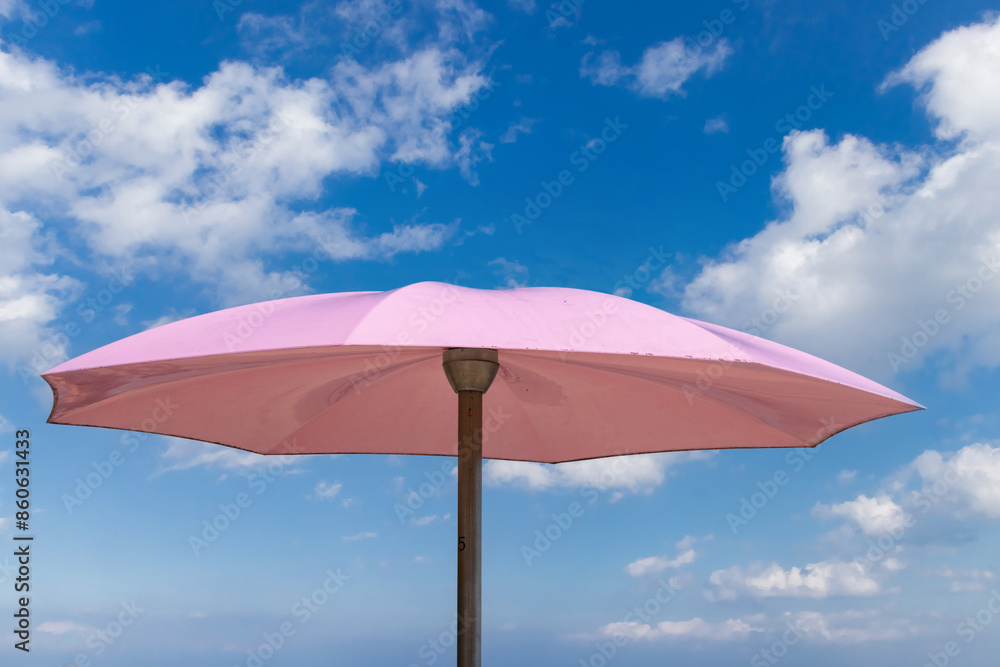 A pink umbrella against a blue sky with fluffy clouds A pink umbrella against a blue sky with fluffy clouds
