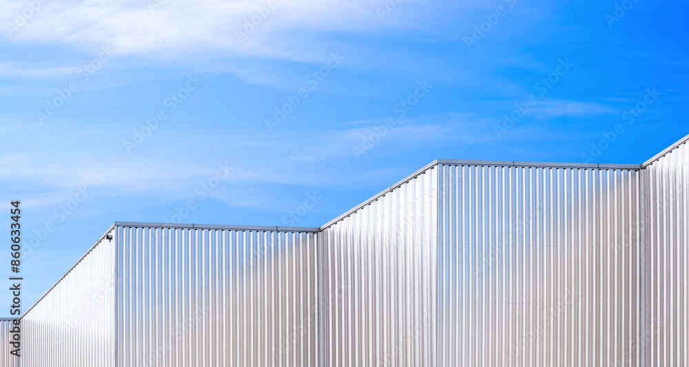 Row of aluminium corrugated metal wall of geometric industrial factory buildings against blue sky background, low angle and perspective side view Row of aluminium corrugated metal wall of geometric industrial factory buildings against blue sky background, low angle and perspective side view