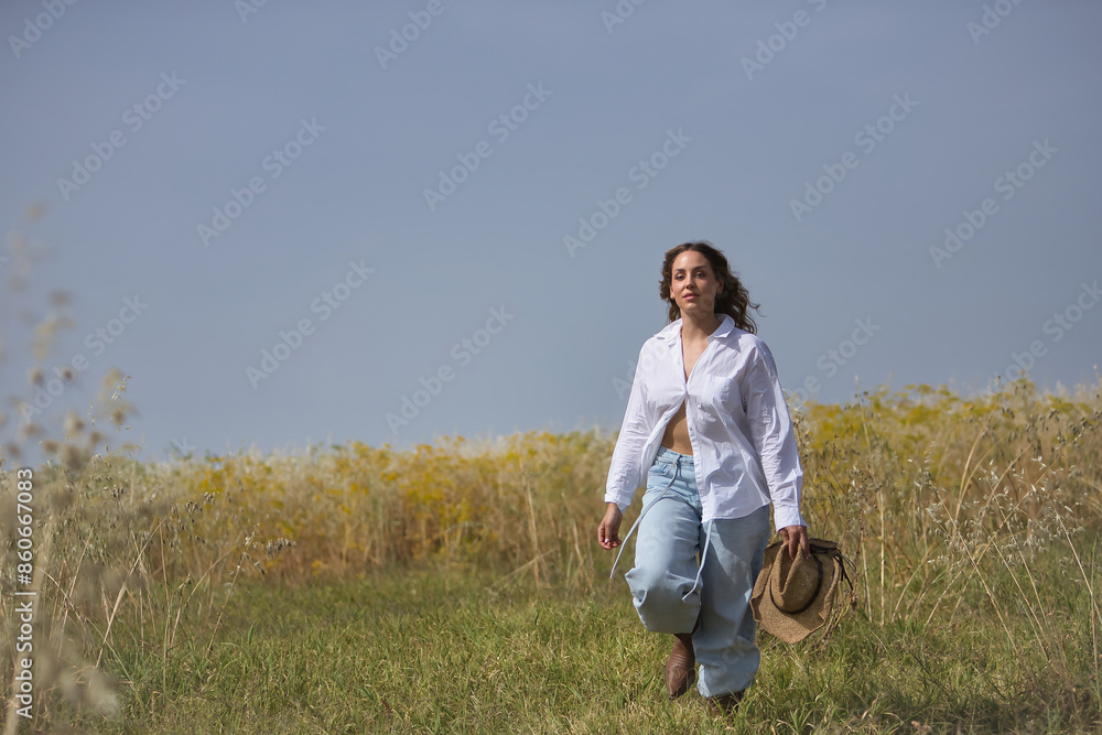 Young woman, farmer, beautiful, blonde, with green eyes, white shirt, jeans and hat, walking in the countryside, alone, free and empowered. Concept beauty, countryside, protection, peace, nature. Young woman, farmer, beautiful, blonde, with green eyes, white shirt, jeans and hat, walking in the countryside, alone, free and empowered. Concept beauty, countryside, protection, peace, nature.