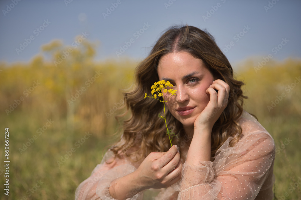 Portrait of a young, beautiful, blonde woman with green eyes, wearing a silk shirt, covering her face with a fennel branch, in the middle of the field. Concept beauty, countryside, peace, nature. Portrait of a young, beautiful, blonde woman with green eyes, wearing a silk shirt, covering her face with a fennel branch, in the middle of the field. Concept beauty, countryside, peace, nature.