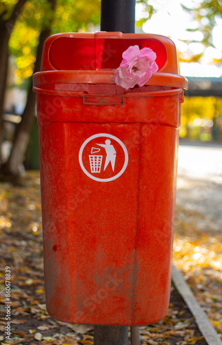 Orange Trash Can With Pink Flower in Autumn Park