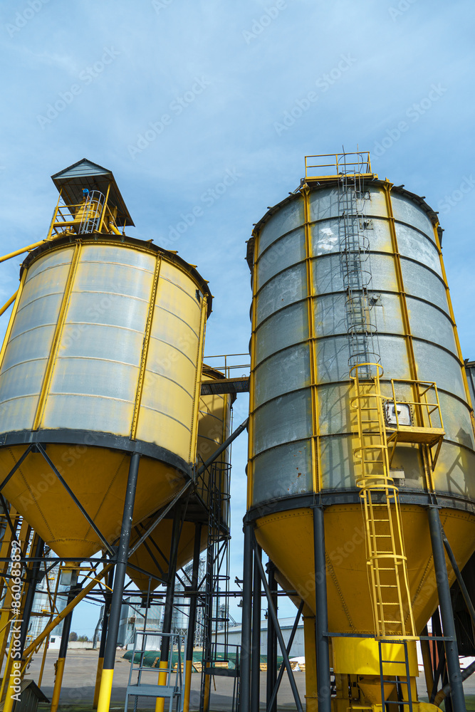 silver silos on agro manufacturing plant for processing drying cleaning and storage of agricultural products, flour, cereals and grain. Large iron barrels of grain. Granary elevator silver silos on agro manufacturing plant for processing drying cleaning and storage of agricultural products, flour, cereals and grain. Large iron barrels of grain. Granary elevator