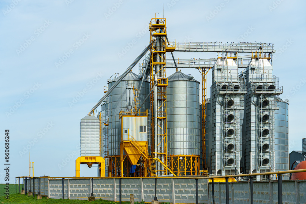 silver silos on agro manufacturing plant for processing drying cleaning and storage of agricultural products, flour, cereals and grain. Large iron barrels of grain. Granary elevator silver silos on agro manufacturing plant for processing drying cleaning and storage of agricultural products, flour, cereals and grain. Large iron barrels of grain. Granary elevator