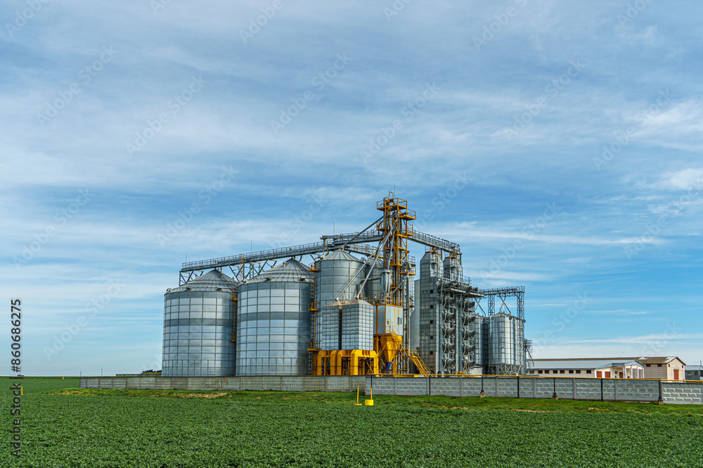 silver silos on agro manufacturing plant for processing drying cleaning and storage of agricultural products, flour, cereals and grain. Large iron barrels of grain. Granary elevator silver silos on agro manufacturing plant for processing drying cleaning and storage of agricultural products, flour, cereals and grain. Large iron barrels of grain. Granary elevator