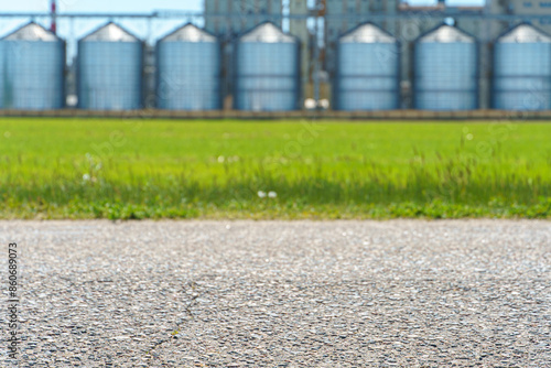 silver silos on agro manufacturing plant for processing drying cleaning and storage of agricultural products, flour, grain. A granary on the background of a road, a place for text or advertising.