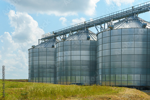 silver silos on agro manufacturing plant for processing drying cleaning and storage of agricultural products, flour, cereals and grain. Large iron barrels of grain. Granary elevator © Pokoman