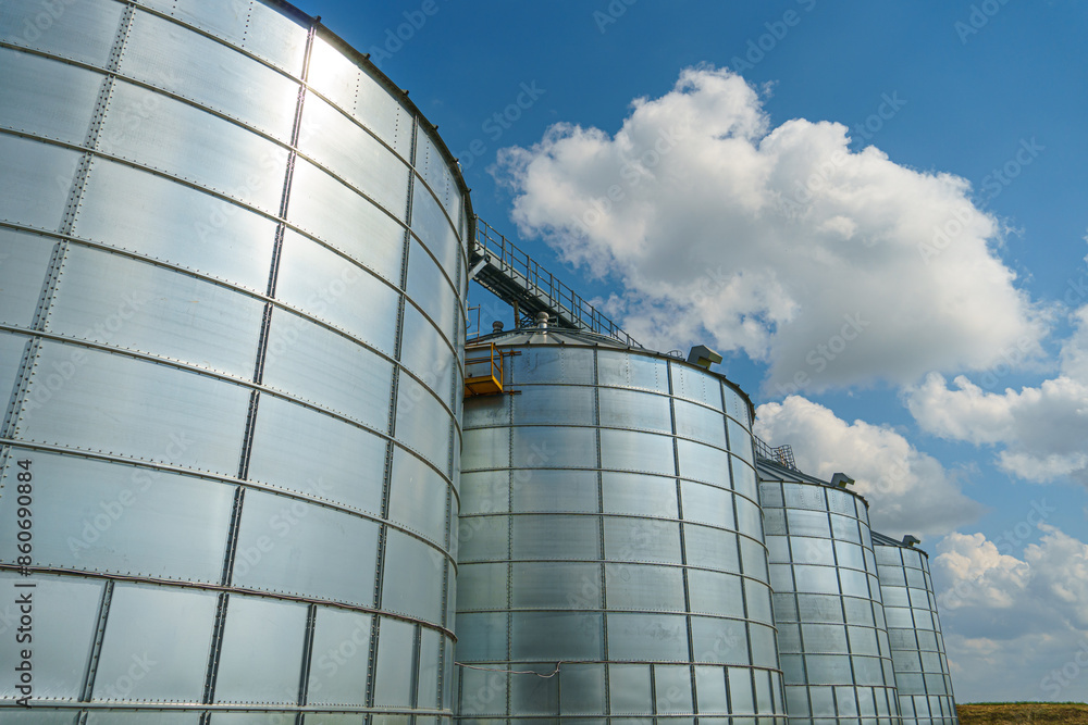 silver silos on agro manufacturing plant for processing drying cleaning and storage of agricultural products, flour, cereals and grain. Large iron barrels of grain. Granary elevator silver silos on agro manufacturing plant for processing drying cleaning and storage of agricultural products, flour, cereals and grain. Large iron barrels of grain. Granary elevator