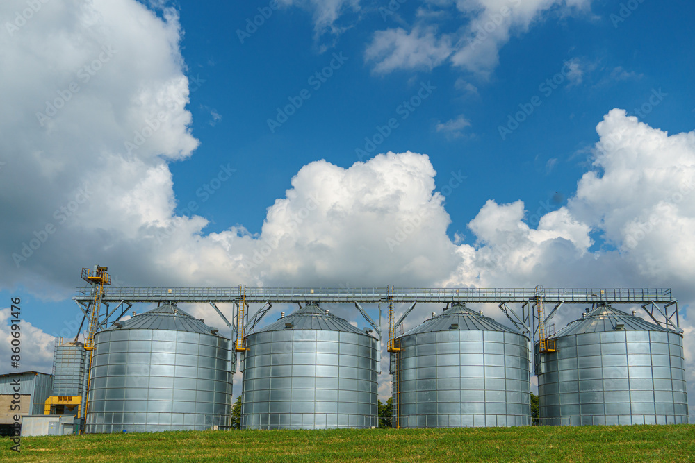 silver silos on agro manufacturing plant for processing drying cleaning and storage of agricultural products, flour, cereals and grain. Large iron barrels of grain. Granary elevator silver silos on agro manufacturing plant for processing drying cleaning and storage of agricultural products, flour, cereals and grain. Large iron barrels of grain. Granary elevator