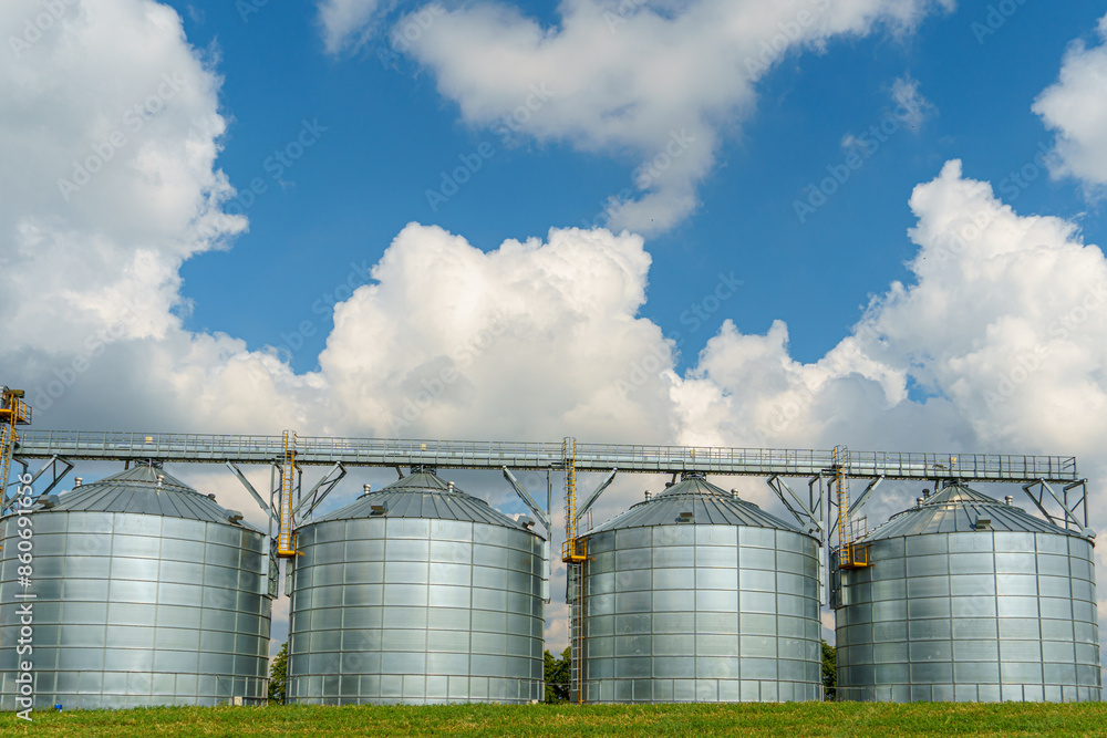 silver silos on agro manufacturing plant for processing drying cleaning and storage of agricultural products, flour, cereals and grain. Large iron barrels of grain. Granary elevator silver silos on agro manufacturing plant for processing drying cleaning and storage of agricultural products, flour, cereals and grain. Large iron barrels of grain. Granary elevator