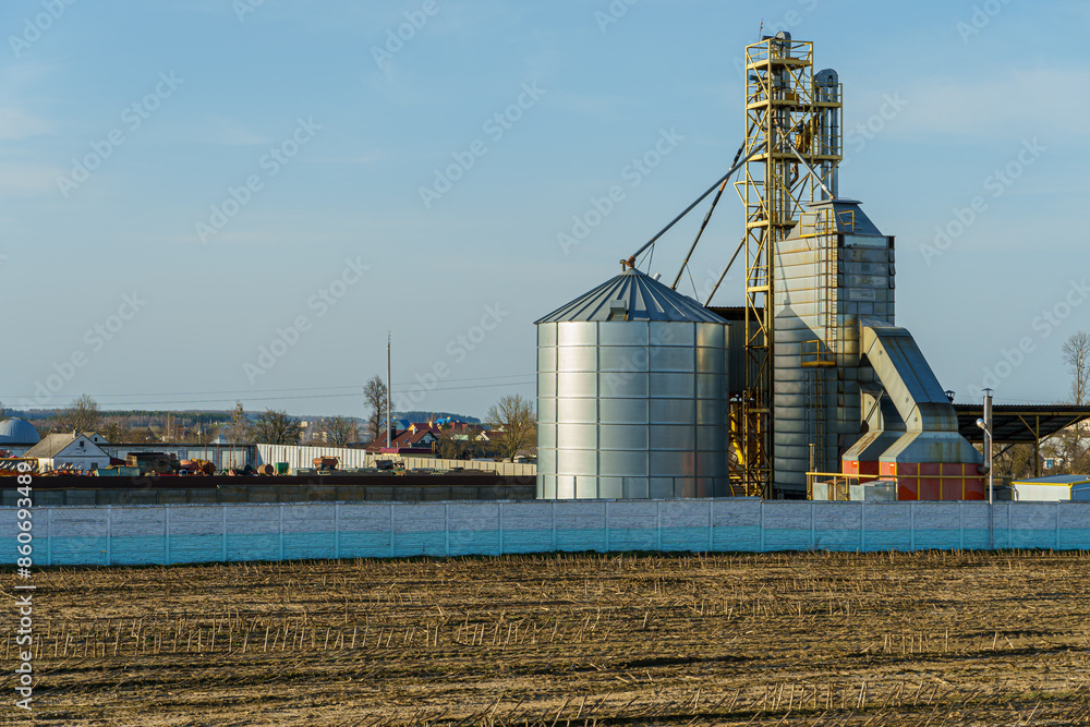 silver silos on agro manufacturing plant for processing drying cleaning and storage of agricultural products, flour, cereals and grain. Large iron barrels of grain. Granary elevator silver silos on agro manufacturing plant for processing drying cleaning and storage of agricultural products, flour, cereals and grain. Large iron barrels of grain. Granary elevator