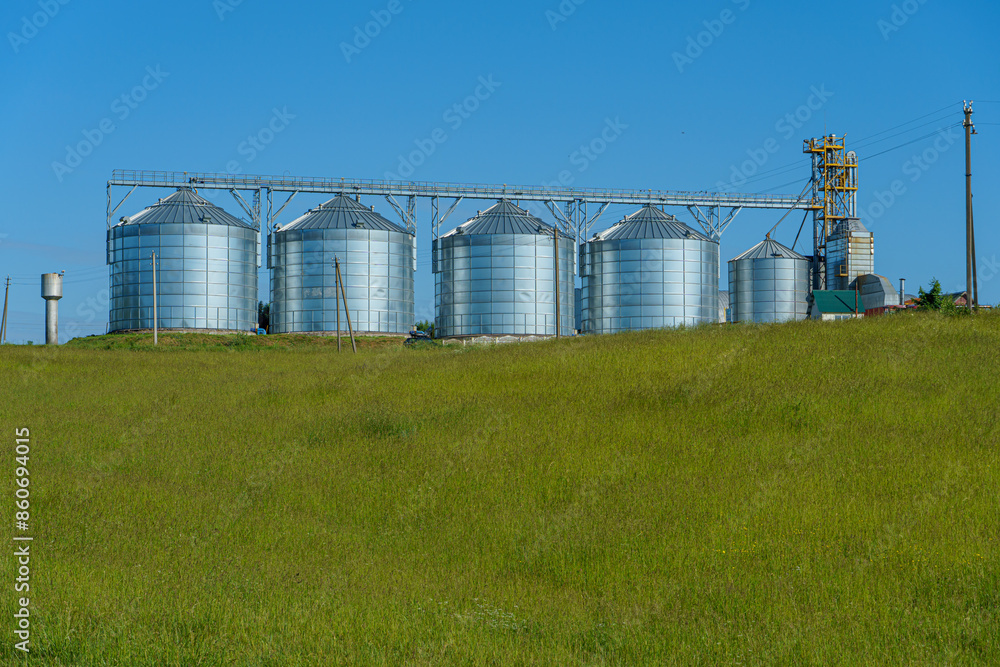 silver silos on agro manufacturing plant for processing drying cleaning and storage of agricultural products, flour, cereals and grain. Large iron barrels of grain. Granary elevator silver silos on agro manufacturing plant for processing drying cleaning and storage of agricultural products, flour, cereals and grain. Large iron barrels of grain. Granary elevator