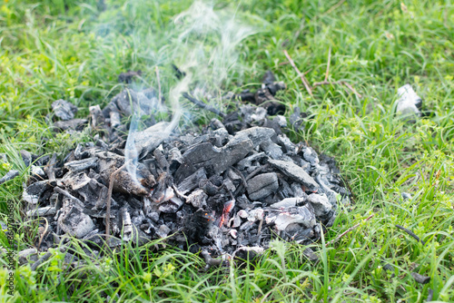 Billede på lærred smoldering coals from a fire on the grass and smoke