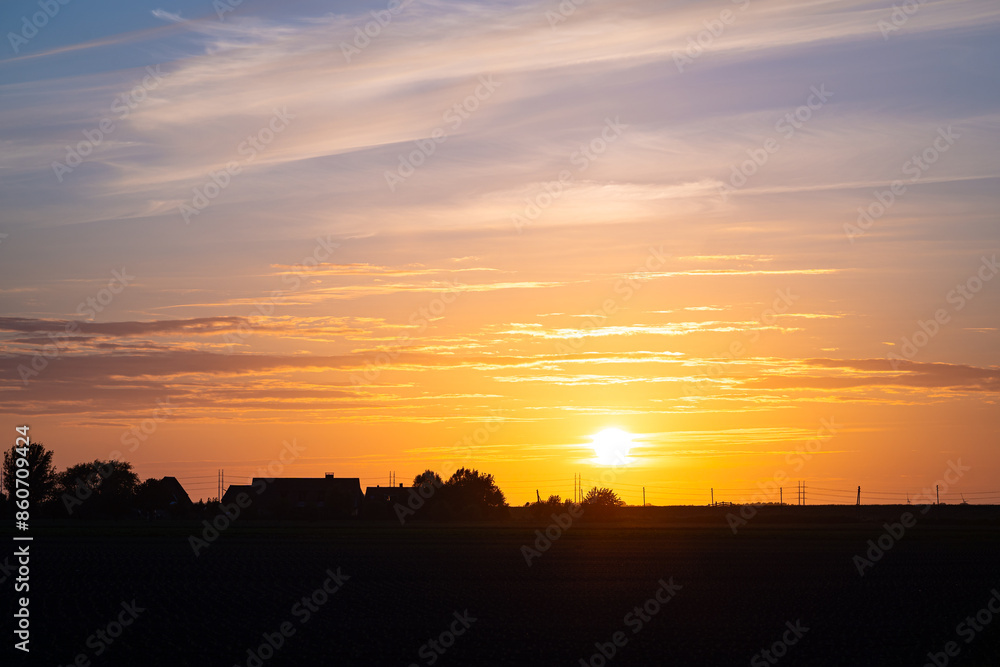 Beautiful sunset over the Dutch countryside. Silhouette of power lines and farm against the colorful evening sky. Beautiful sunset over the Dutch countryside. Silhouette of power lines and farm against the colorful evening sky.