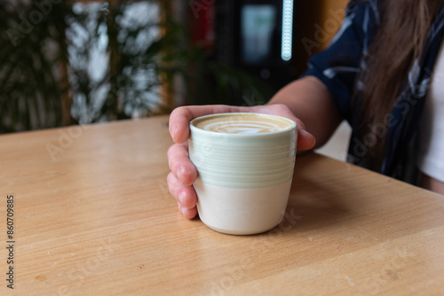 Hand holding a ceramic cup of coffee at a cafe photo