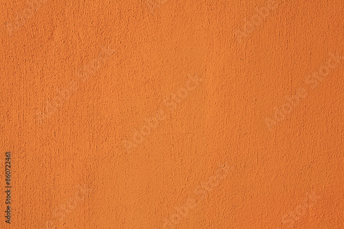 Rich orange wall, texture, background. Decor of contrasting orange textured coating. Structural plaster, rough, uneven surface in bright orange color. Modern exterior cladding of multi-story buildings
