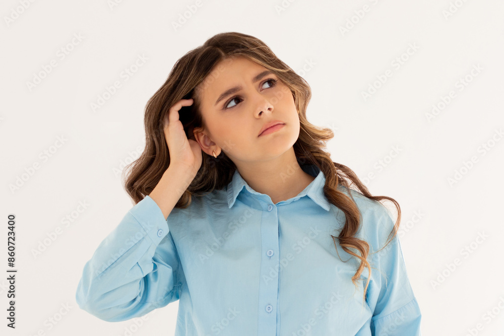 Young beautiful girl with long dark hair wearing blue shirt. freelancer looking away with confused disappointed expression, scratching head. student not remembers information for exam Young beautiful girl with long dark hair wearing blue shirt. freelancer looking away with confused disappointed expression, scratching head. student not remembers information for exam