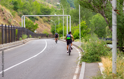 Two Cyclists Riding Down a Winding Road in a Green Valley