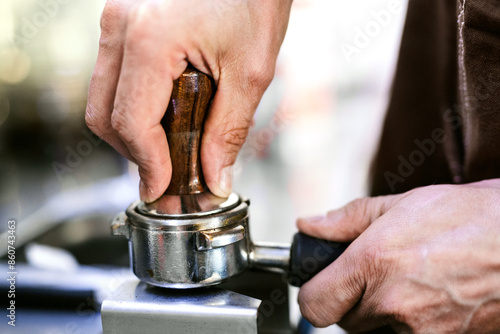 Tableau sur toile Barista tamping the coffee grounds with a tamper into the portafilter