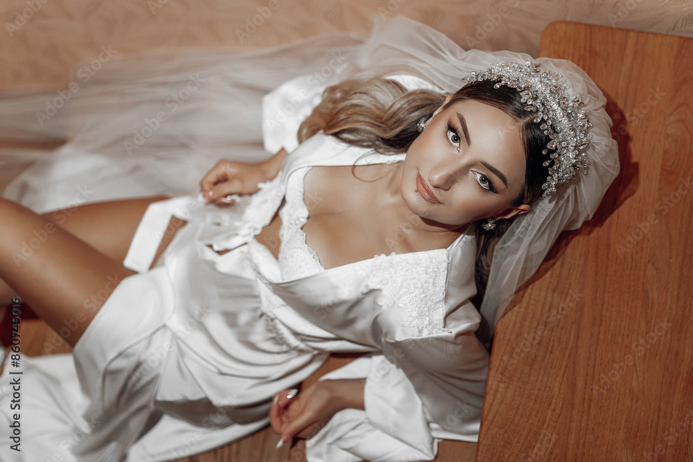 A woman in a wedding dress is laying on a wooden table. She is wearing a veil and a tiara A woman in a wedding dress is laying on a wooden table. She is wearing a veil and a tiara
