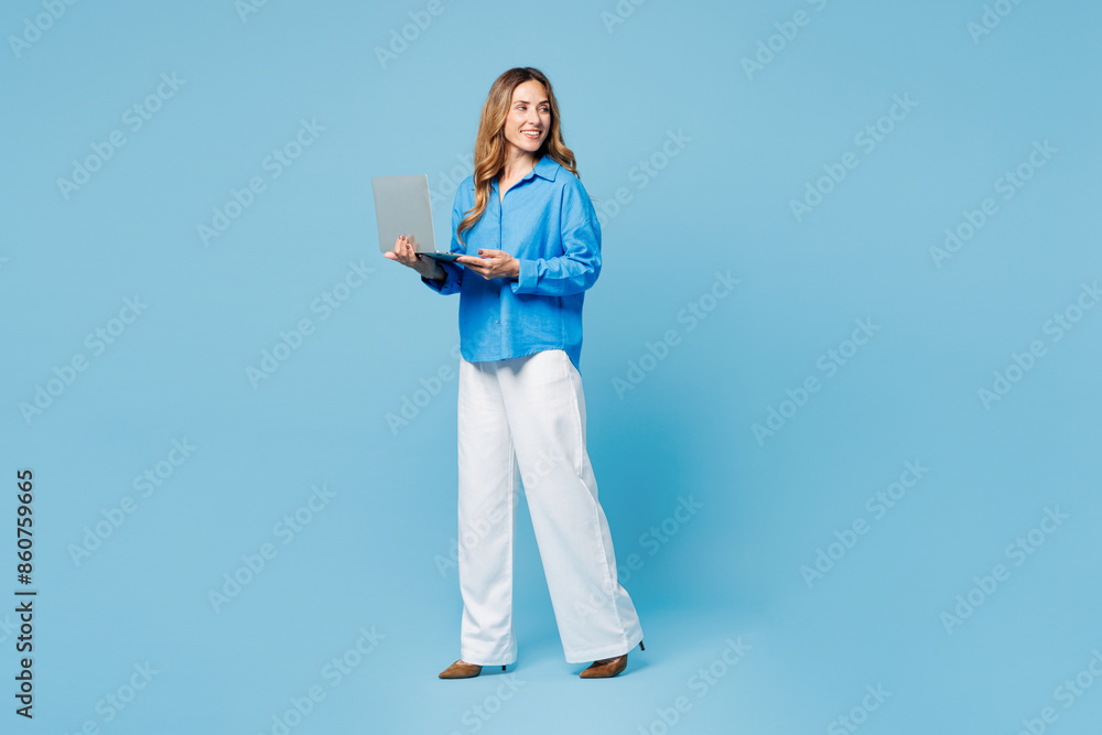 Full body young IT woman she wears shirt casual clothes hold use work on laptop pc computer look aside on area isolated on plain pastel light blue cyan background studio portrait. Lifestyle concept. Full body young IT woman she wears shirt casual clothes hold use work on laptop pc computer look aside on area isolated on plain pastel light blue cyan background studio portrait. Lifestyle concept.