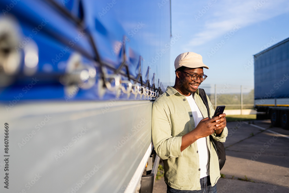 Driver standing by his truck and using mobile phone. Driver standing by his truck and using mobile phone.