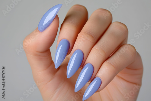 A female hand adorned with extended nails elegantly displays blue lilac nail polish photo