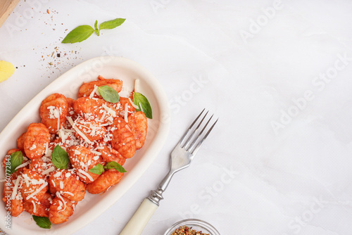 Plate of tasty gnocchi with tomato sauce and cheese on white background photo