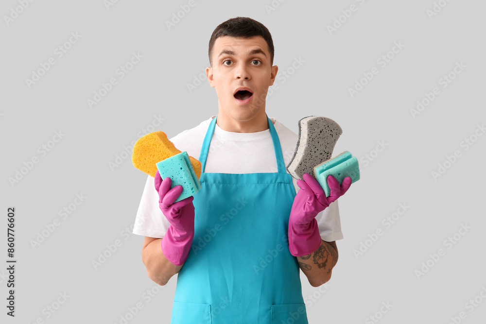 Surprised young man with many sponges on light background Surprised young man with many sponges on light background