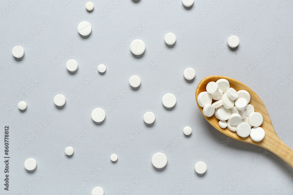 Wooden spoon with pills on grey background Wooden spoon with pills on grey background