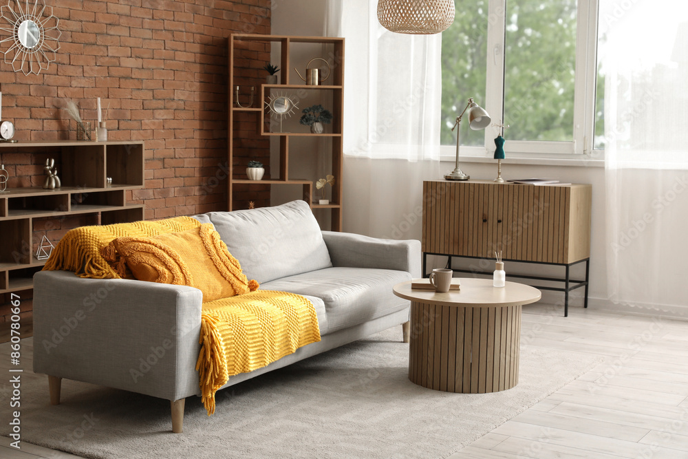 Obraz premium Interior of cozy living room with grey sofa, table and drawers