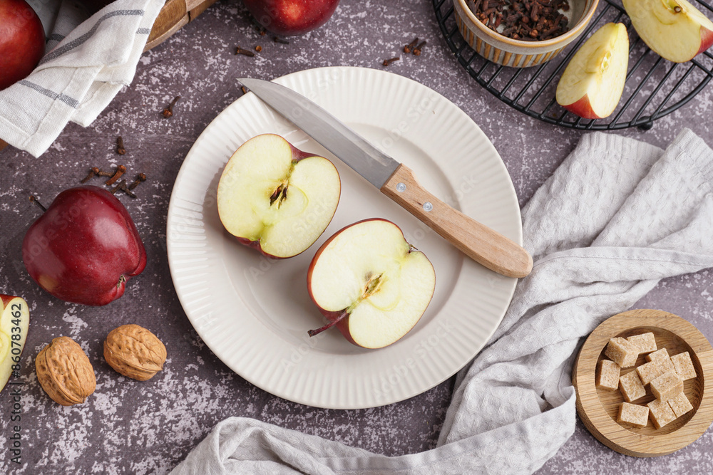 Plate with halves of fresh red apple and walnuts on dark background Plate with halves of fresh red apple and walnuts on dark background