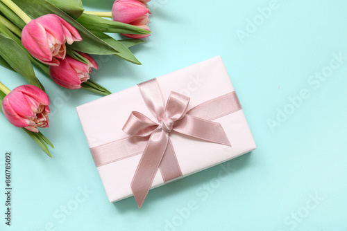 Gift box and beautiful tulips on blue background. International Women's Day © Pixel-Shot