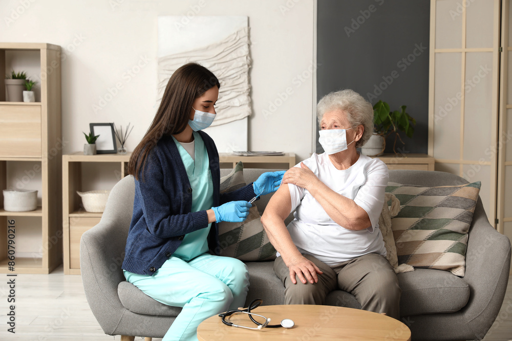 Obraz premium Young nurse vaccinating senior woman at home