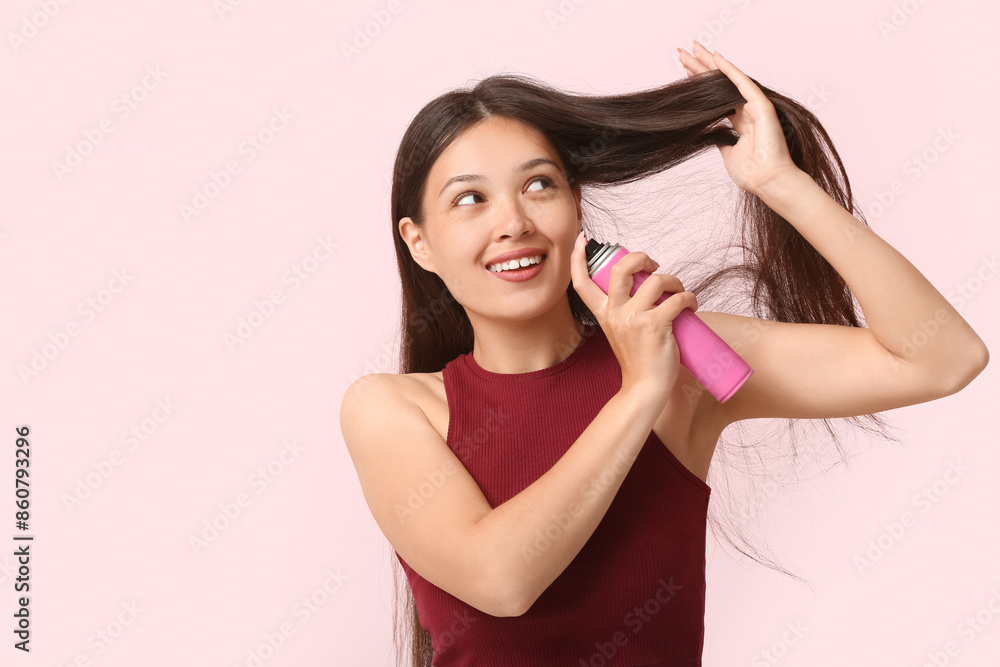 Beautiful young happy woman applying hair spray on pink background Beautiful young happy woman applying hair spray on pink background