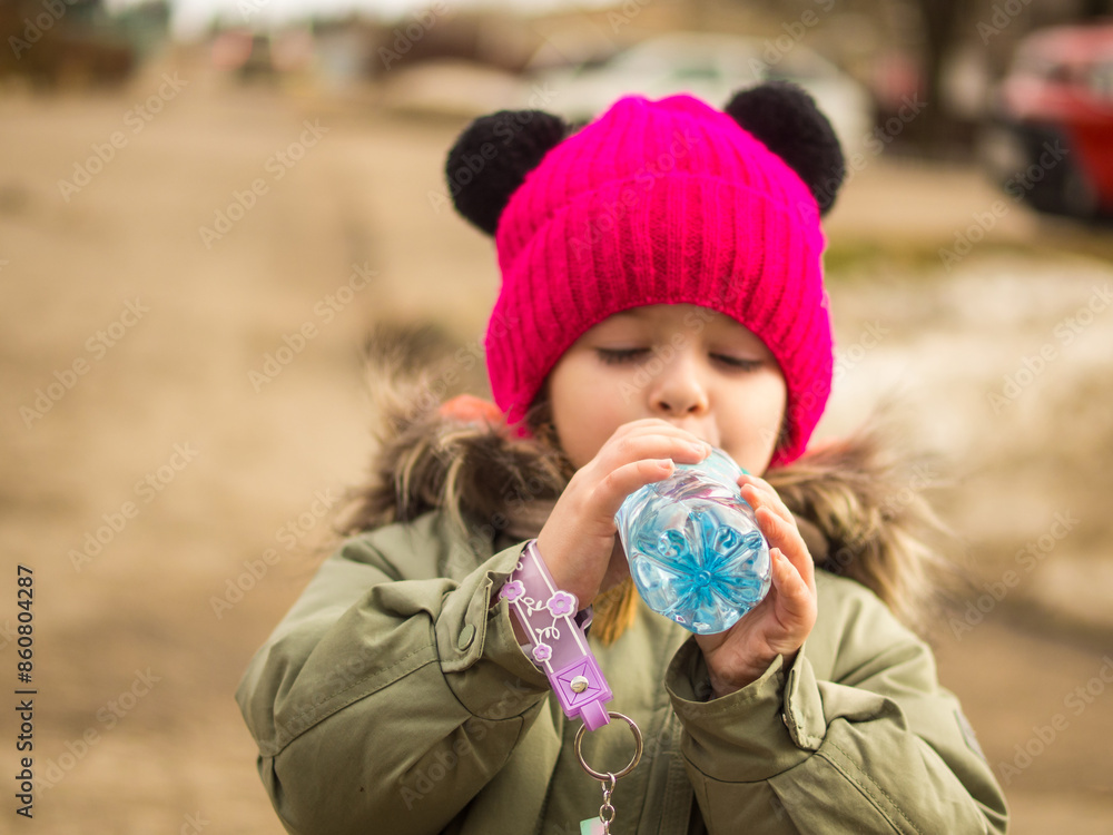 child drinks water from a bottle on the street child drinks water from a bottle on the street