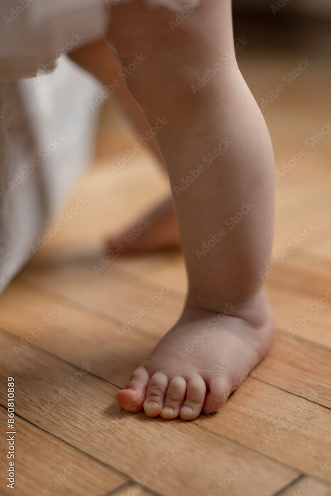 close-up of little cute baby girl feet, 12 month old baby learning to walk with support close-up of little cute baby girl feet, 12 month old baby learning to walk with support