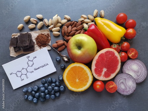 Structural chemical formula of quercetin with fresh fruit and vegetable. Quercetin is a plant pigment (flavonoid). It's found in many plants such as red onion, berries, tomato, nuts, citrus, apple.