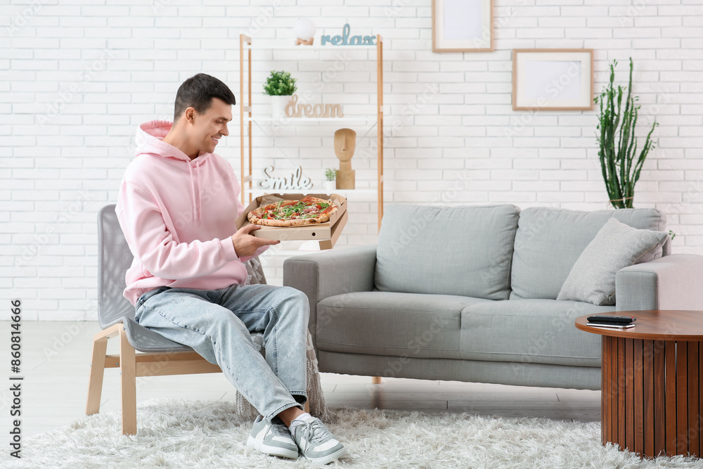 Young man holding cardboard box with tasty pizza at home Young man holding cardboard box with tasty pizza at home
