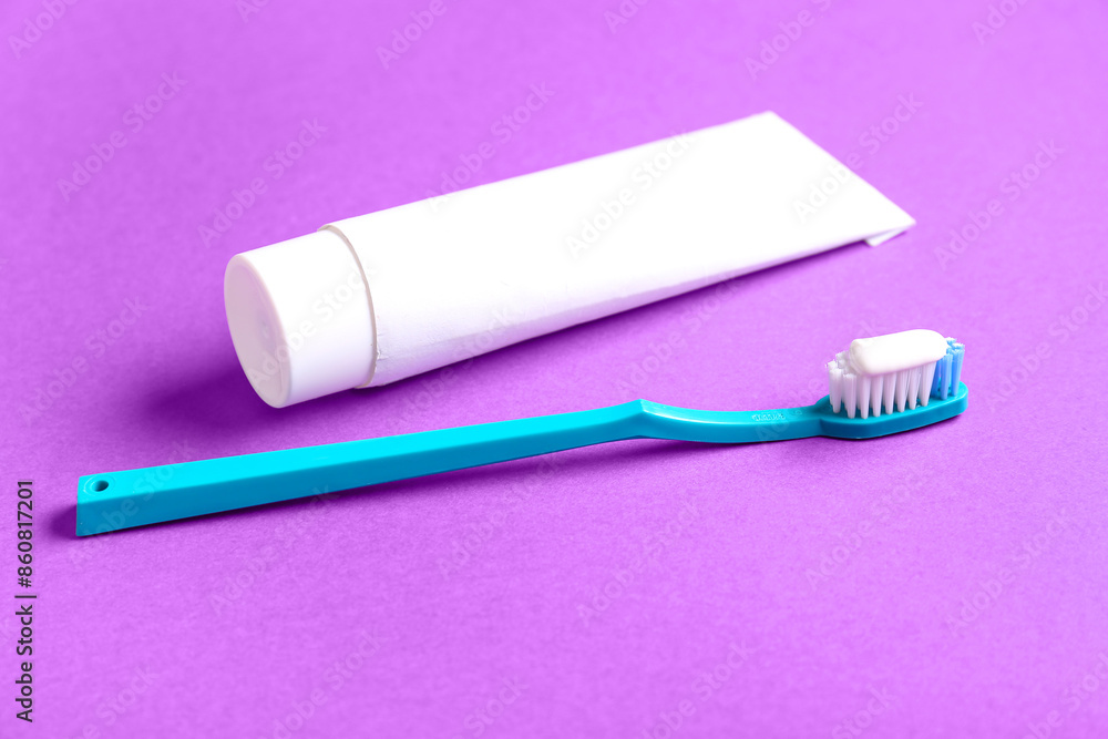 Tube of tooth paste and blue brush on purple background Tube of tooth paste and blue brush on purple background