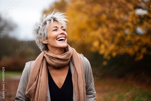 Portrait of a happy senior woman laughing outdoors in autumnal park