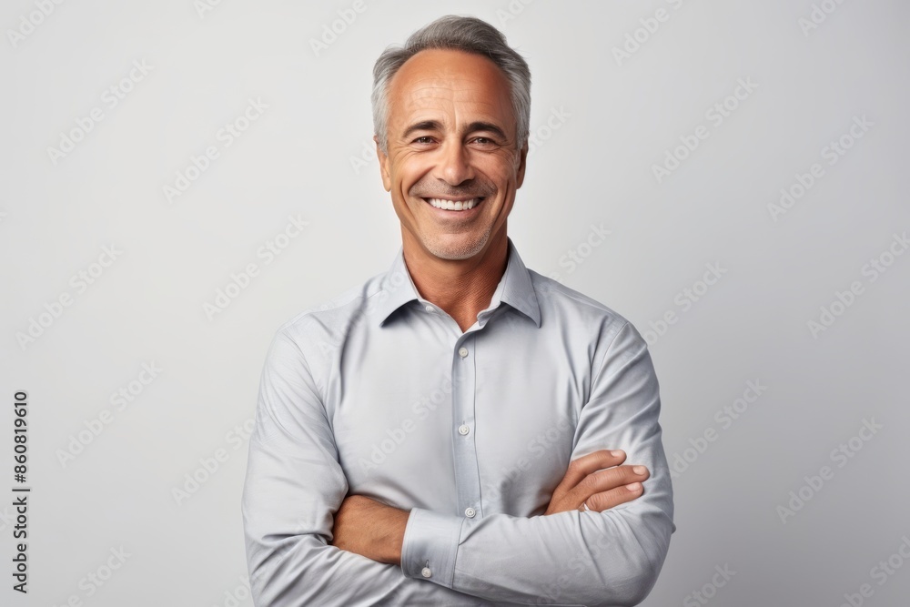 Handsome mature man looking at camera and smiling while standing against grey background Handsome mature man looking at camera and smiling while standing against grey background