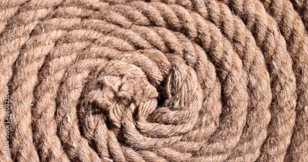 Thick strong rope made of cotton twisted into spiral lies on floor. Vintage sailboat rope made of weathered hemp material. Rope intended for lifting weights at bright light Thick strong rope made of cotton twisted into spiral lies on floor. Vintage sailboat rope made of weathered hemp material. Rope intended for lifting weights at bright light
