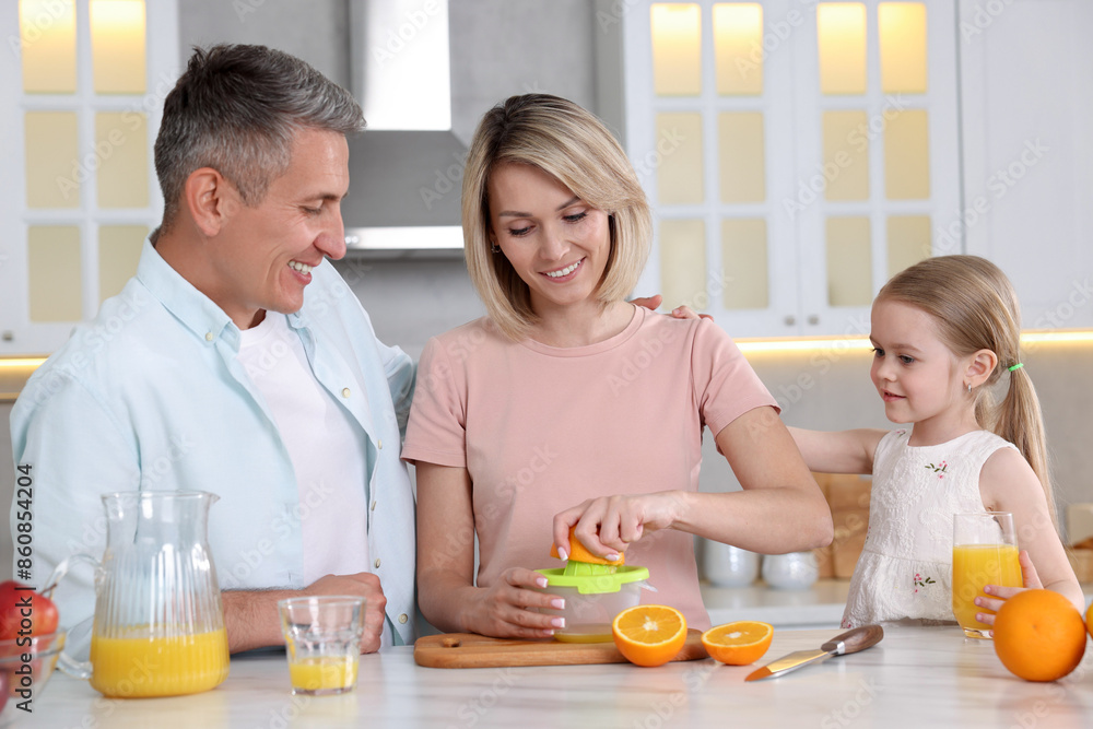 Happy family making juice at white marble table in kitchen Happy family making juice at white marble table in kitchen