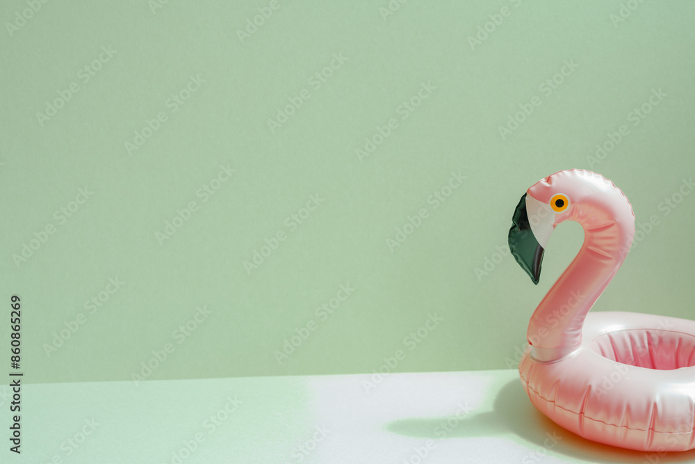 Summer vacation concept. Pink flamingo bird shape swimming pool tube on mint green background