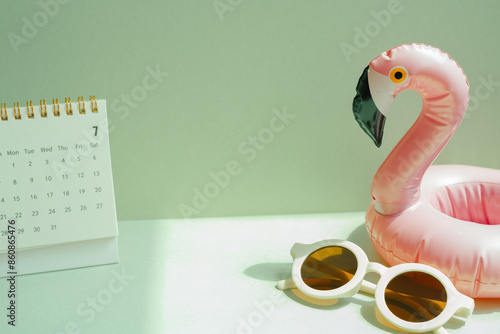 Obraz na płótnie Summer vacation planning concept. Pink flamingo bird shape swimming pool tube and sunglasses, calendar on mint green background w salonie