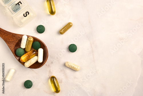 wooden spoon with capsules of vitamins and dietary supplements on a table with organizers for pills top view photo