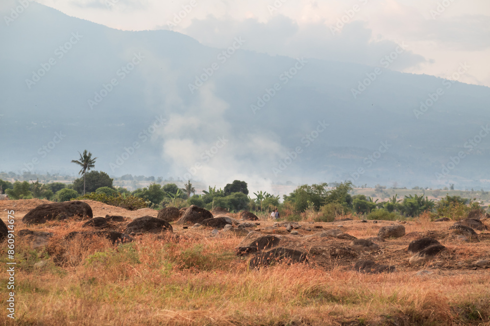 Rocky grassland landscape with mountains covered in fog in the background
