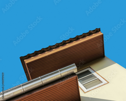 Home and blue sky background. Gutter at the edge of the wooden eave. Residential property. Roof of old house.